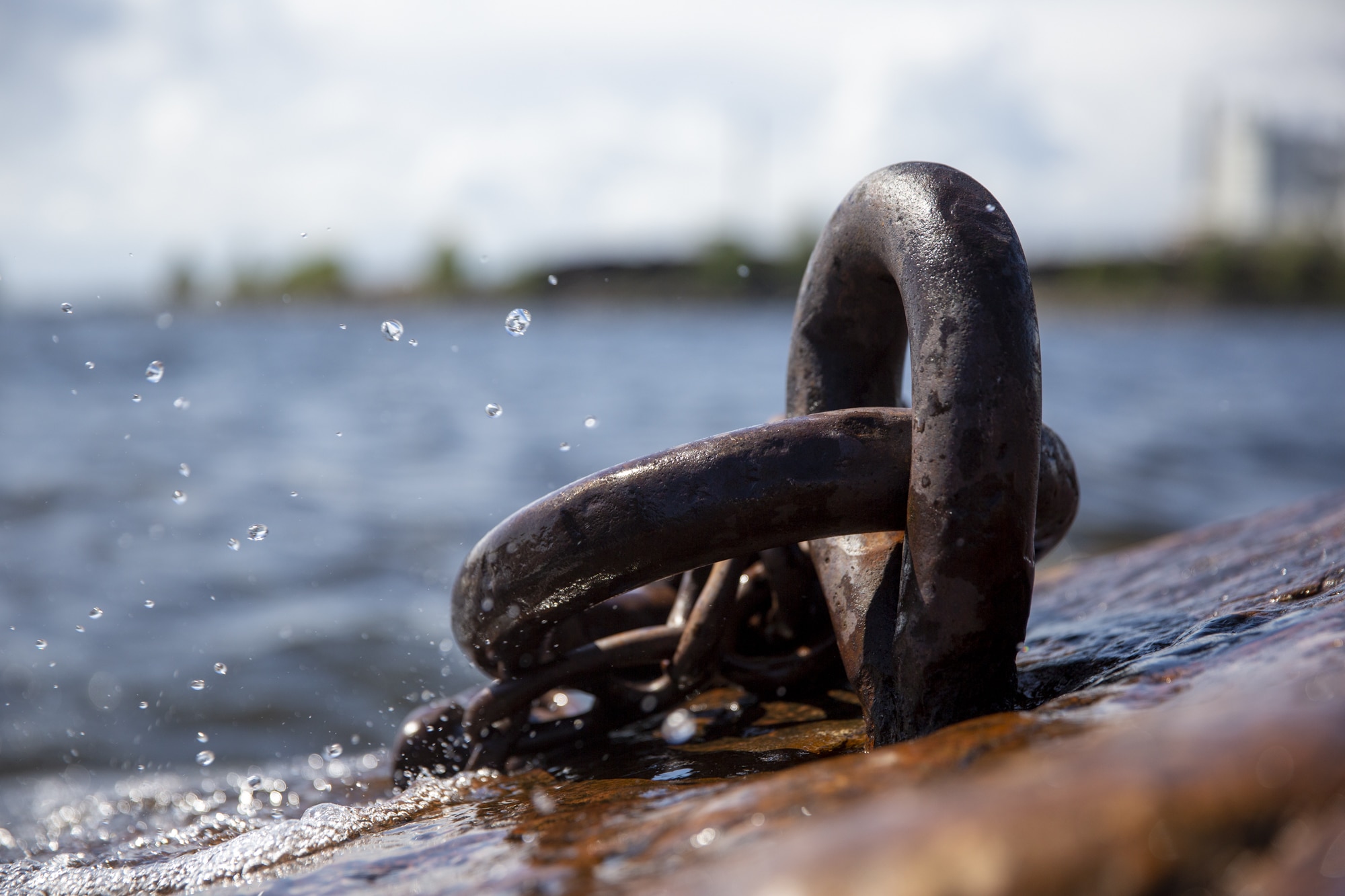 Rusty mooring bolt with splashing waves in the background.